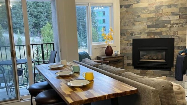 Een moderne woonkamer met een houten eettafel, een bank en een open haard.