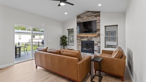 A spacious living room with a stone fireplace, leather sofas, and a ceiling fan. - The Dells Domain (Wisconsin Dells)