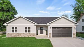 A two-story house with a garage, stone foundation, and a well-maintained lawn. - The Dells Domain (Wisconsin Dells)