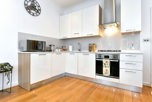 Fully equipped kitchen with microwave, toaster, and oven, plus a convenient clock and ample workspace.
