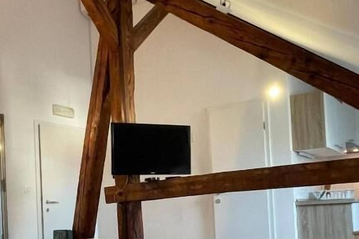 Une chambre avec une structure de plafond en bois, un lit et un téléviseur fixé au plafond.