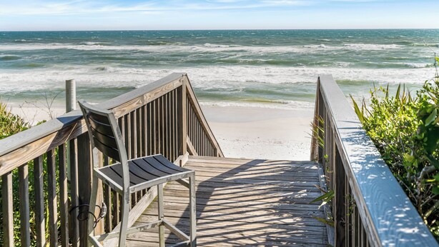 A wooden boardwalk leading to a beach with waves crashing onto the shore.