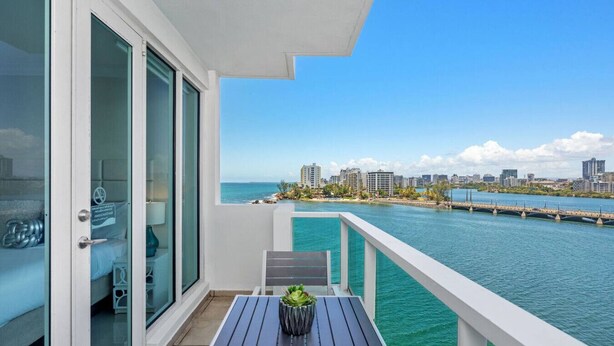 A balcony with a view of a city skyline and water. - Family Studio · Ocean View · Water Backup (San Juan)