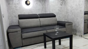 Ein modernes Wohnzimmer mit einem grauen Sofa, einem schwarzen Couchtisch und einem Marmorboden.