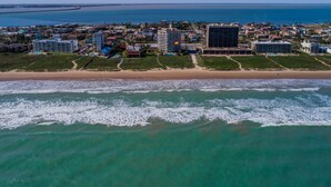 Luchtbeeld van een kustplaatsje met gebouwen, een strand en de oceaan.