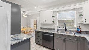 Uma cozinha moderna com armários cinza, bancada de mármore e máquina de lavar louça embutida.
