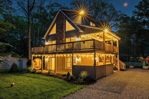 Ein zweistöckiges Haus mit Balkon, Lichterkette und einer Holzterrasse.