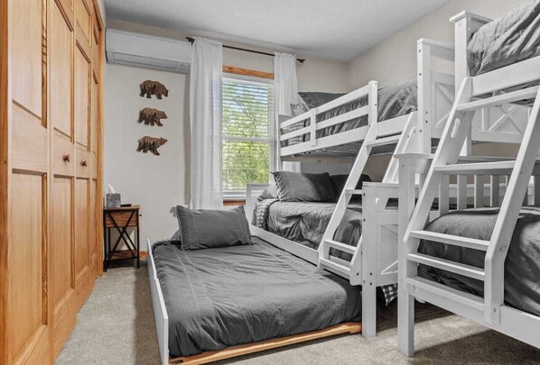 Une chambre avec des lits superposés, une armoire en bois et une fenêtre avec des rideaux.
