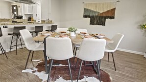 A dining area with a wooden table, white chairs, and a cowhide rug.