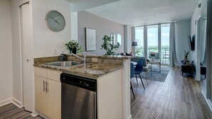 Een moderne keuken met een vaatwasser, granieten aanrechtblad en een eethoek met uitzicht.