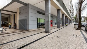 A modern building with a covered entrance, large pillars, and a cobblestone walkway.