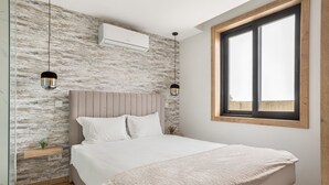 A bedroom with a bed, a window, a wall-mounted air conditioner, and two pendant lights.
