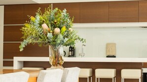 A modern kitchen with wooden cabinets, a central island with bar stools, and a vase with flowers on the island. - Tanunda House - Luxury 5 BR in Barossa Wine Region (Tanunda)