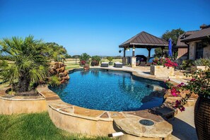A swimming pool with a stone border, a gazebo, and outdoor furniture. - Lone Wolf Ranch | Pet-friendly | Pool (Fredericksburg)