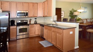 A modern kitchen with wooden cabinets, stainless steel appliances, and a central island. - Rehoboth Beach Townhouse Pool Parking Porch (Rehoboth Beach)