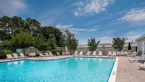 A rectangular swimming pool with clear blue water, surrounded by white lounge chairs and a tiled deck. - Rehoboth Beach Townhouse Pool Parking Porch (Rehoboth Beach)