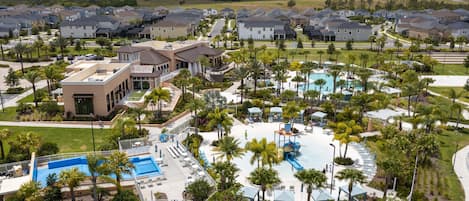 A residential area with a large swimming pool surrounded by palm trees and houses.