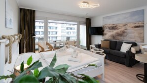 Una camera d'albergo moderna con un balcone, un quadro di grandi dimensioni, un divano e un tavolino da caffè.