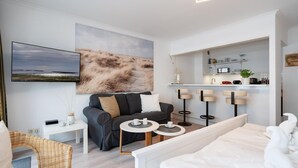 Una camera d'albergo moderna con un'ampia opera d'arte, un divano, un'area pranzo e angolo cottura.