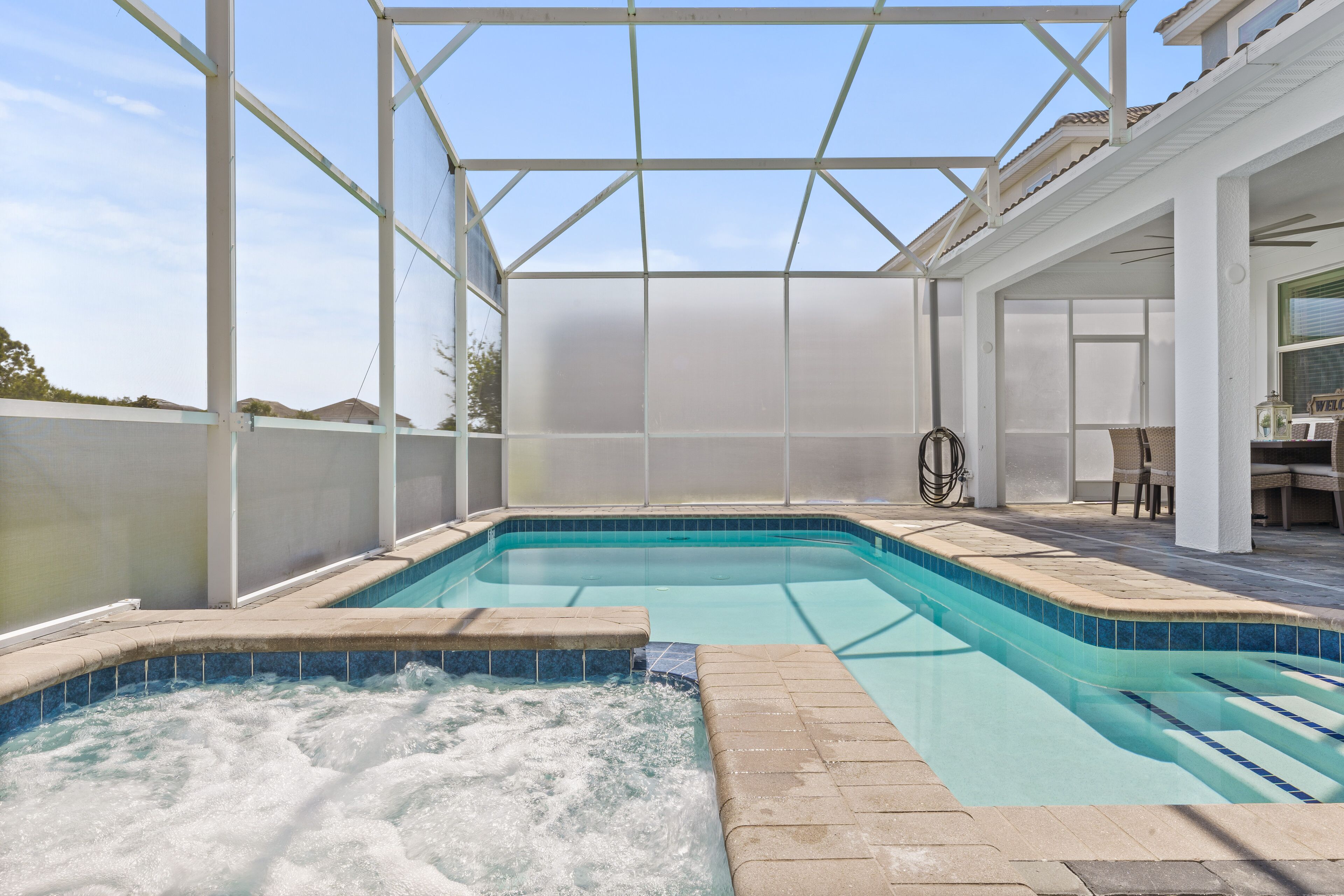 Ein überdachter Pool mit Whirlpool, umgeben von einer weißen Pergola.