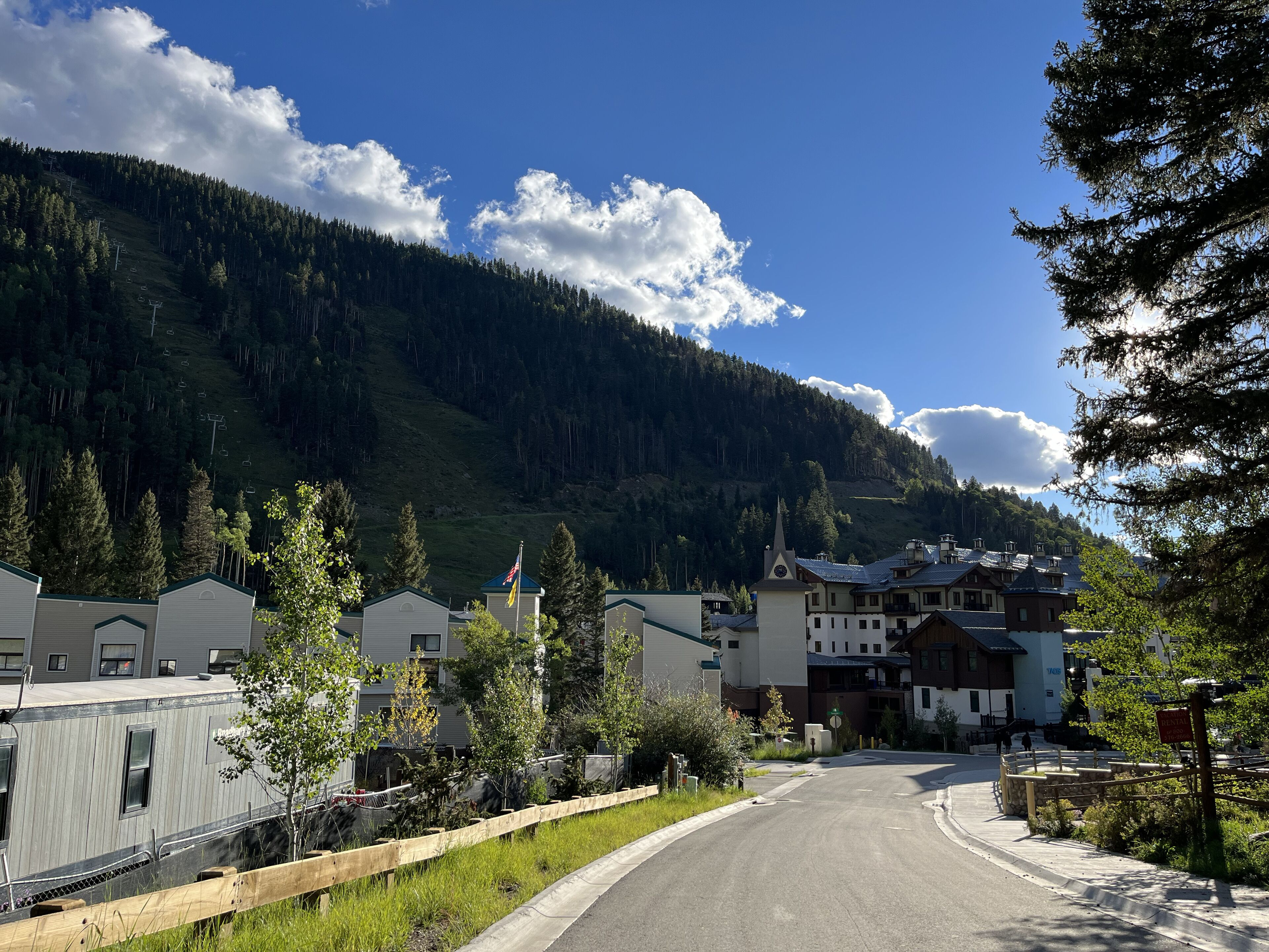 A mountain town with a road leading to a building with a ski lift in the background.