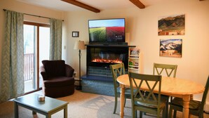 A living room with a fireplace, a television, a dining table with chairs, and a sofa. - Suite Situation in the Ski Village (Taos Ski Valley)