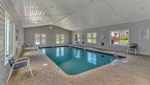Piscina interior com regras claramente afixadas, um relógio na parede e vista exterior através de grandes janelas.