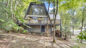 A modern cabin with a triangular roof, surrounded by a forest.