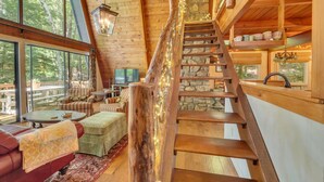 A wooden interior with a staircase, large windows, and a cozy seating area.