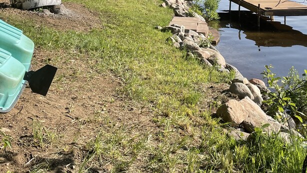 A wooden dock extending into a calm lake, surrounded by trees and a grassy area with a picnic table and chairs. - Cozy Lakefront Cottage on Little Pequaywan ~ Great for all seasons (Duluth)