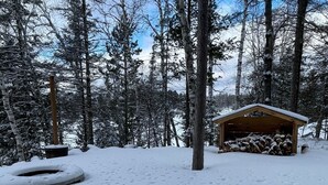 A snow-covered forest with a wooden cabin and a tire swing. - Cozy Lakefront Cottage on Little Pequaywan ~ Great for all seasons (Duluth)