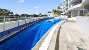 A modern hotel with a swimming pool, a covered walkway, and a view of the surrounding area.
