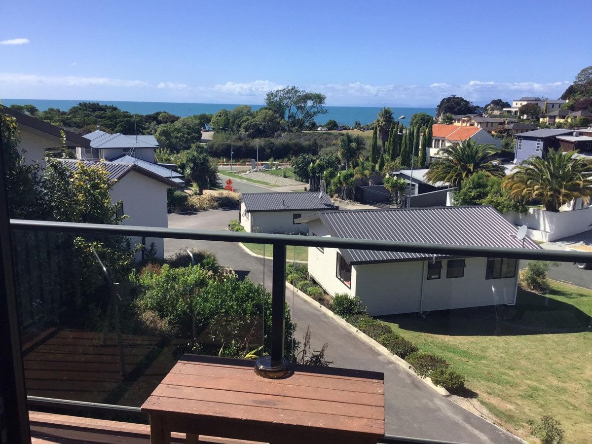 A residential area with houses, a clear sky, and a view of the sea.