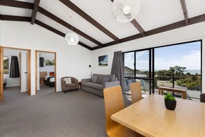 A spacious living area with a balcony, a dining table, and a sofa. - Two Bedroom Apartment Sea View (Kaiteriteri)