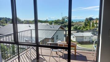 A balcony with a table and chairs, overlooking a residential area with houses and a clear sky.