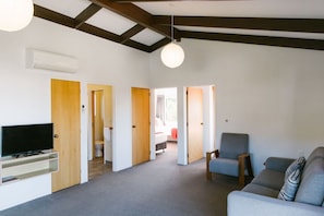 A spacious living area with a television, seating, and a ceiling fan. - Two Bedroom Apartment Sea View unit 8 (Kaiteriteri)