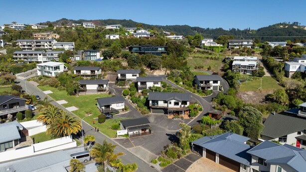 A residential area with modern houses, a central road, and surrounding greenery. - Two Bedroom Garden View (Kaiteriteri)