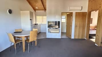 A spacious living area with a dining table and chairs, a sofa, and a kitchen in the background.