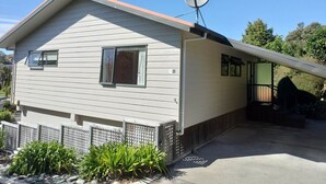 A single-story house with a satellite dish, a front porch, and a small garden area. - Superior Two Bedroom Sea View (Kaiteriteri)