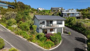 A two-story house with a balcony, surrounded by lush greenery and a curved driveway. - Superior Two Bedroom Sea View (Kaiteriteri)