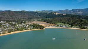 Vue aérienne d’une ville côtière avec une plage, des bateaux et les collines environnantes.
