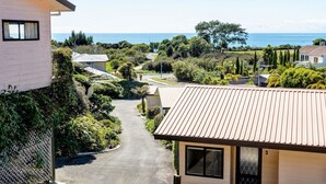 A residential area with a paved driveway leading to a house with a tiled roof. - Studio Sea View Upper Level (Kaiteriteri)