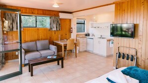 A compact living space with a sofa, dining table, and kitchenette. - Budget Studio Unit Garden view (Kaiteriteri)