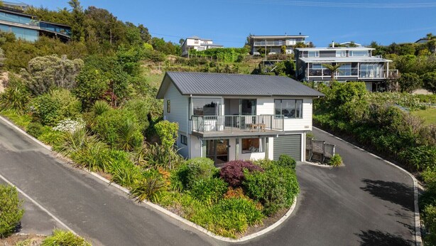 A two-story house with a balcony, surrounded by lush greenery and a curved driveway. - Budget Studio Unit Garden view (Kaiteriteri)