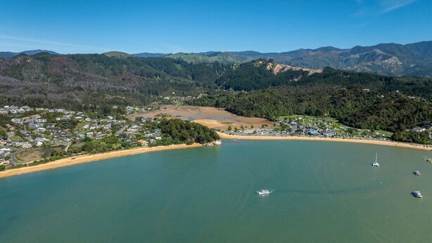 An aerial view of a coastal town with a beach, boats, and surrounding hills. - Studio Sea View Upper Level (Kaiteriteri)
