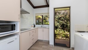 A compact kitchen with a microwave, sink, and cabinets. - Studio Sea View Upper Level (Kaiteriteri)