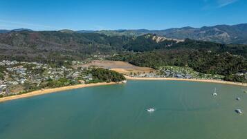 An aerial view of a coastal town with a bay, boats, and a mountainous backdrop.