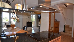 A modern kitchen with a central island, stainless steel range hood, and a dining area with a heart-shaped centerpiece. - Casa Oslo - L'Estartit, Torre Vella (Estartit (L´))