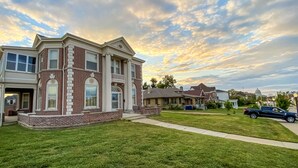 A two-story house with a brick facade, large windows, and a well-maintained lawn.