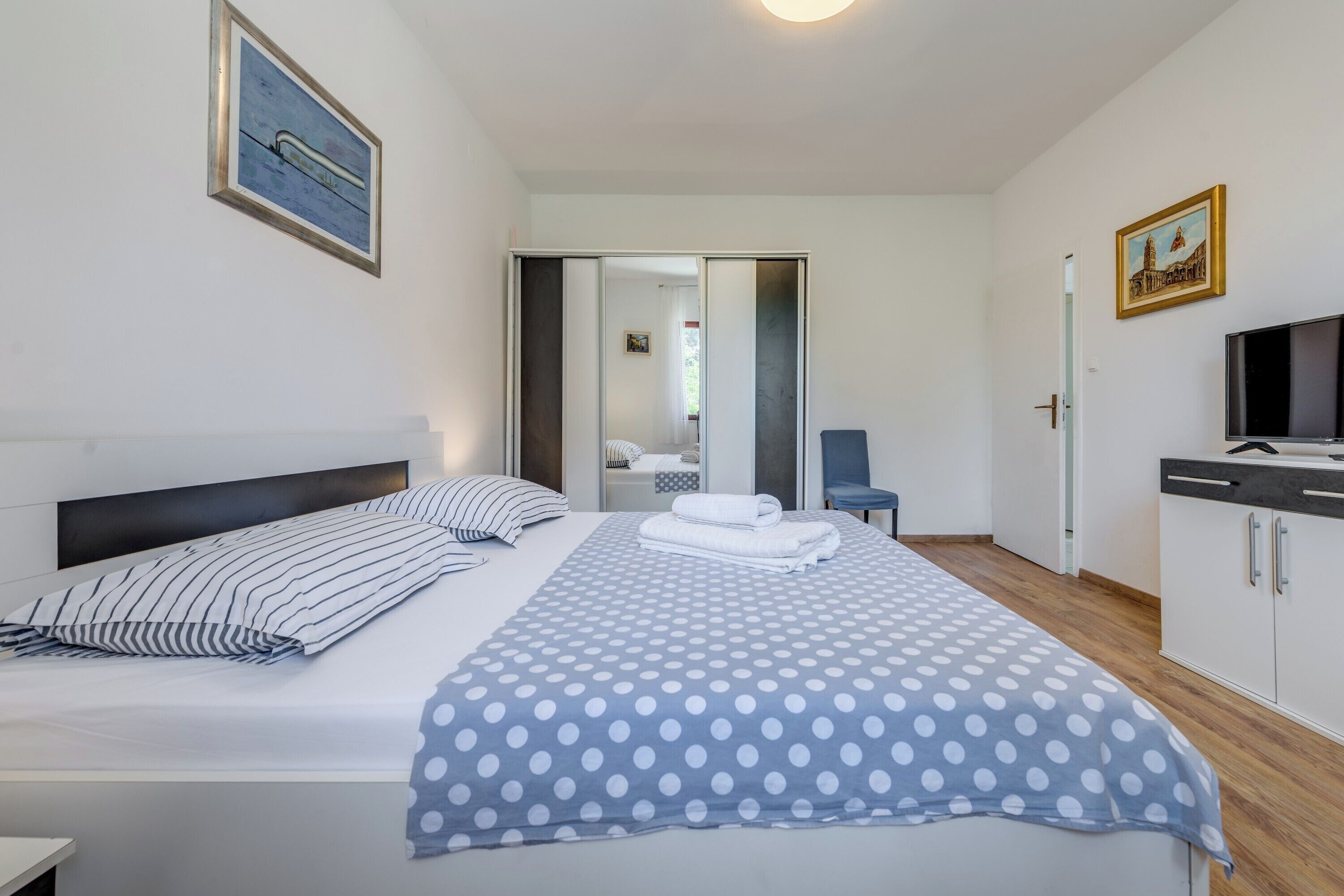 Een moderne hotelkamer met een groot bed, een televisie en een garderobe.